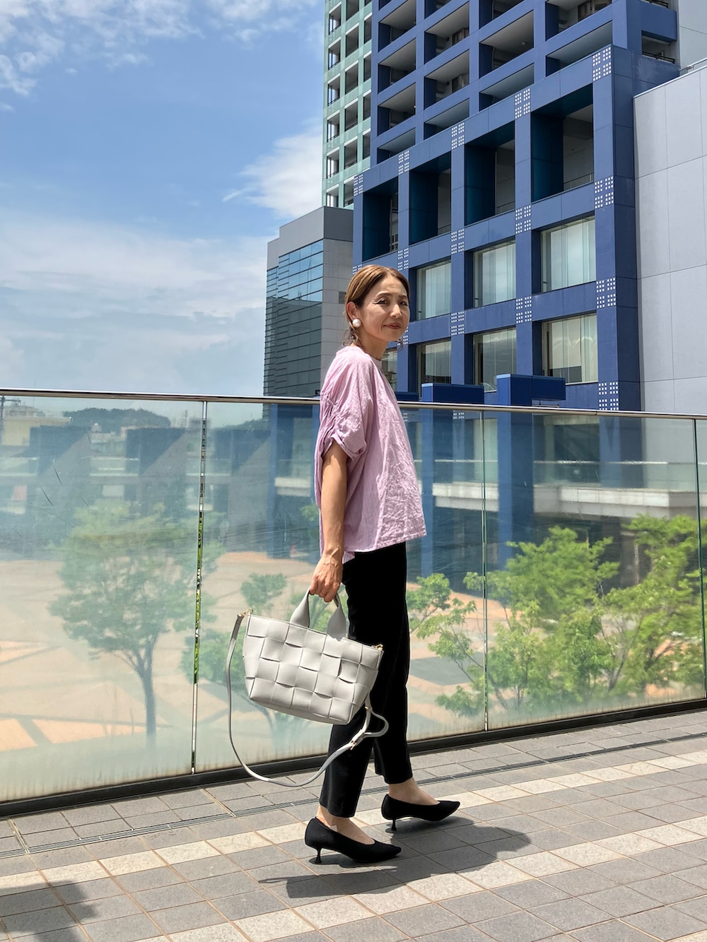 グレー系のハンドバッグ、パープル系のシャツ/ブラウス、ブラック系のパンツを着用したレディースの夏コーディネートの3枚目の写真