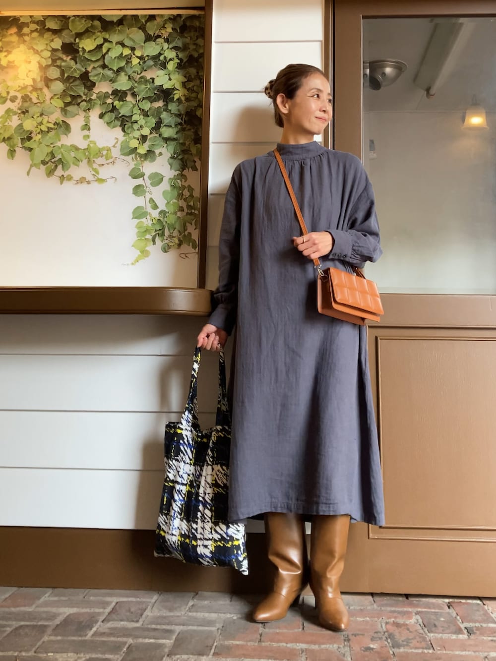 グレー系のワンピース/ドレス、ブラウン系のクラッチバッグ、イエロー系のブーツを着用したレディースの秋コーディネートの3枚目の写真