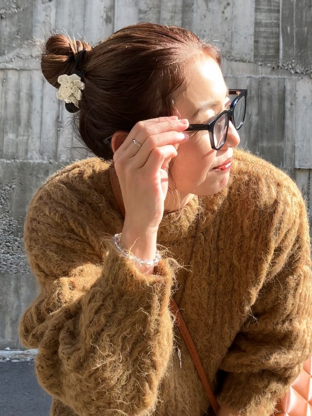 ブラック系のジャンパースカート、ブラウン系のニット/セーター、ブラウン系のクラッチバッグを着用したレディースの冬コーディネートの3枚目の写真