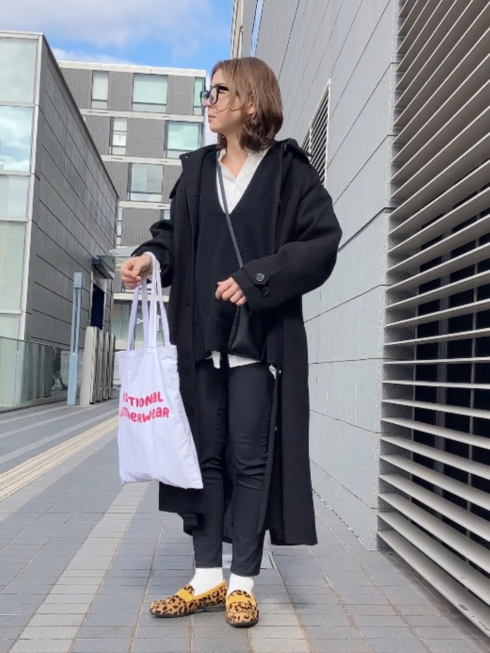 ホワイト系のシャツ/ブラウス、ブラック系のニット/セーター、ブラック系のステンカラーコートを着用したレディースの冬コーディネートの4枚目の写真