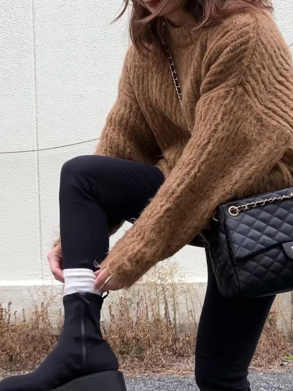 ブラック系のボストンバッグ、ブラック系のブーツ、ブラウン系のニット/セーターを着用したレディースの冬コーディネートの3枚目の写真