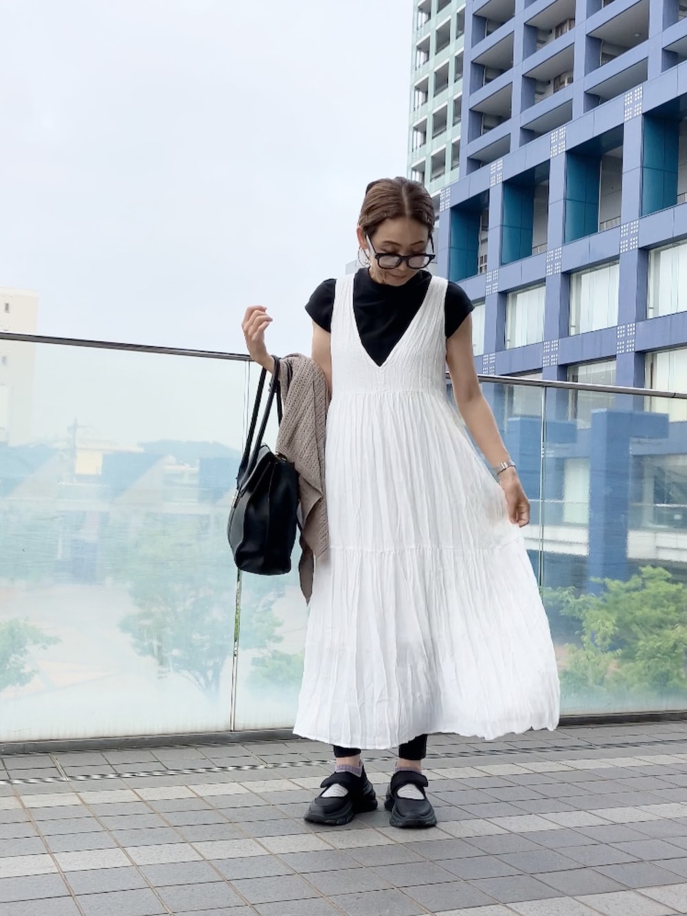 ホワイト系のワンピース、ブラック系のビジネスバッグ、ブラック系のシューズを着用したレディースの夏コーディネートの2枚目の写真