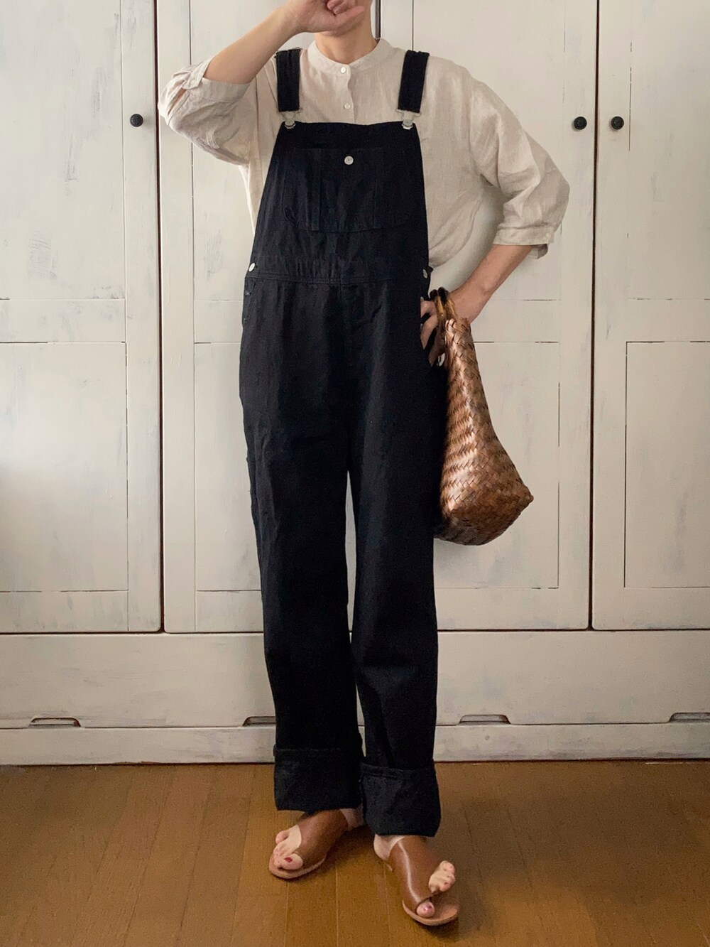 ブラック系のサロペット/オーバーオール、ベージュ系のチュニック、ブラウン系のかごバッグを着用したレディースの春コーディネートの3枚目の写真