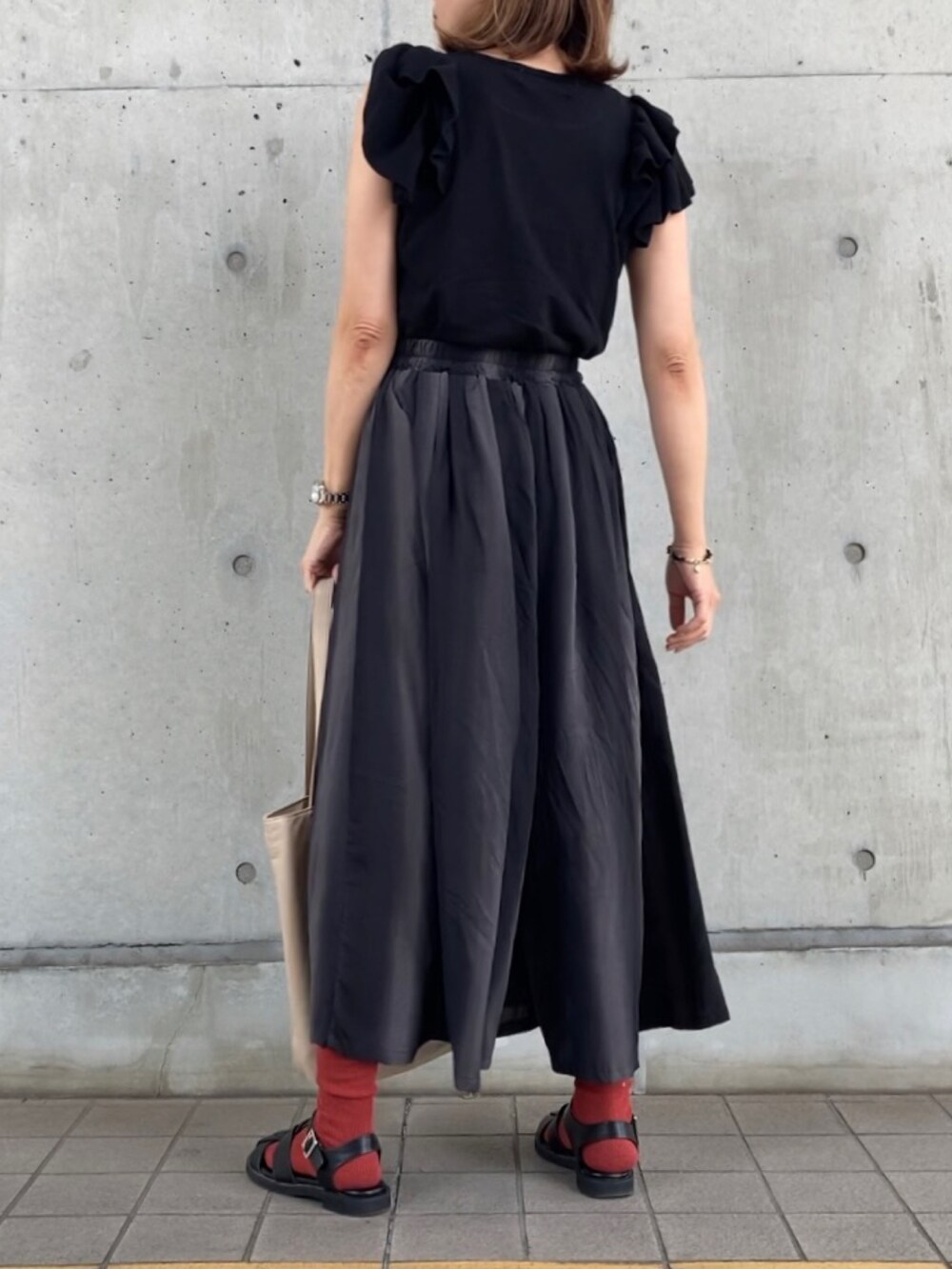 グレー系のパンツ、ブラック系のニット/セーター、ブラック系のサンダルを着用したレディースの春コーディネートの3枚目の写真