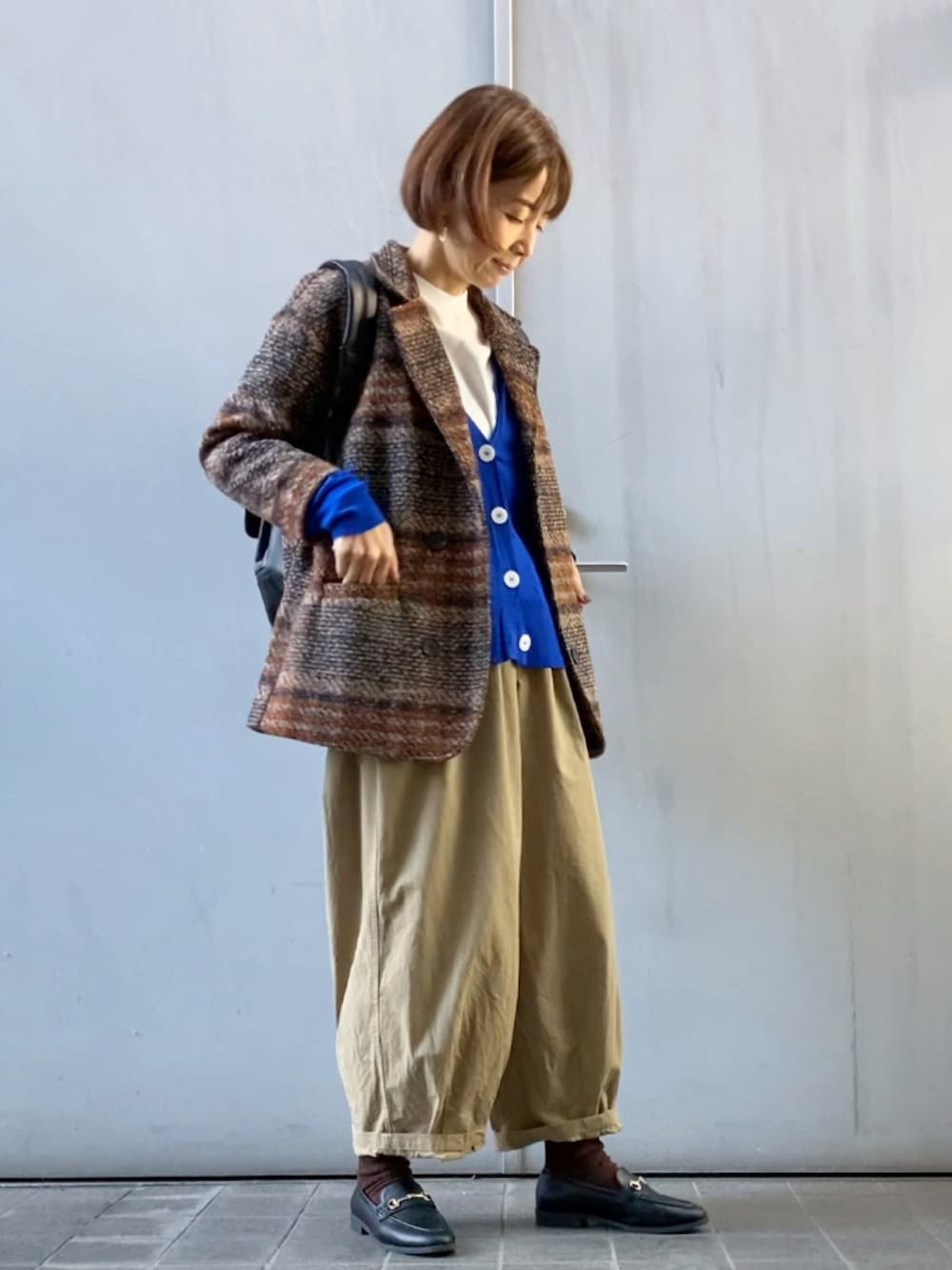 ブラウン系のテーラードジャケット、ブルー系のカーディガン/ボレロ、ブラウン系のバックパック/リュックを着用したレディースの秋コーディネートの2枚目の写真