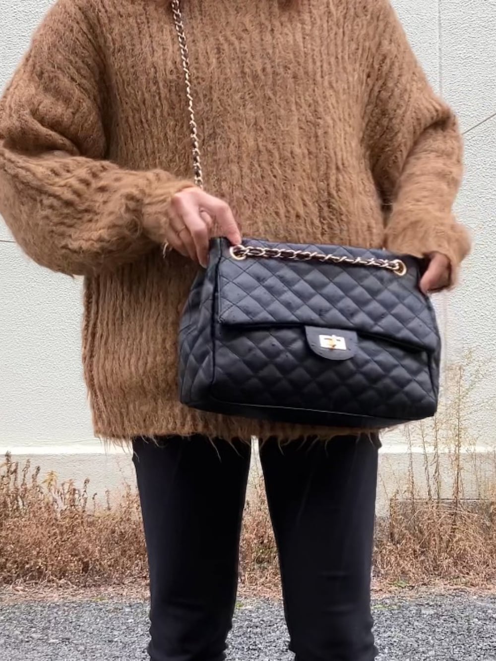 ブラック系のボストンバッグ、ブラック系のブーツ、ブラウン系のニット/セーターを着用したレディースの冬コーディネートの2枚目の写真