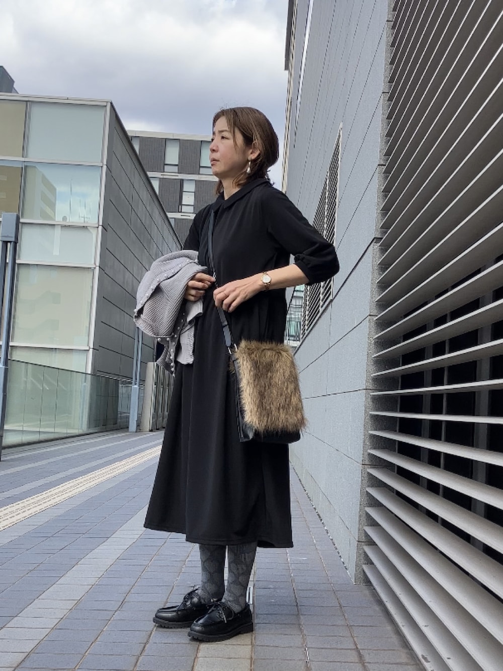 ブラック系のワンピース/ドレス、グレー系のカーディガン/ボレロ、ブラック系のモカシン/デッキシューズを着用したレディースの冬コーディネートの5枚目の写真