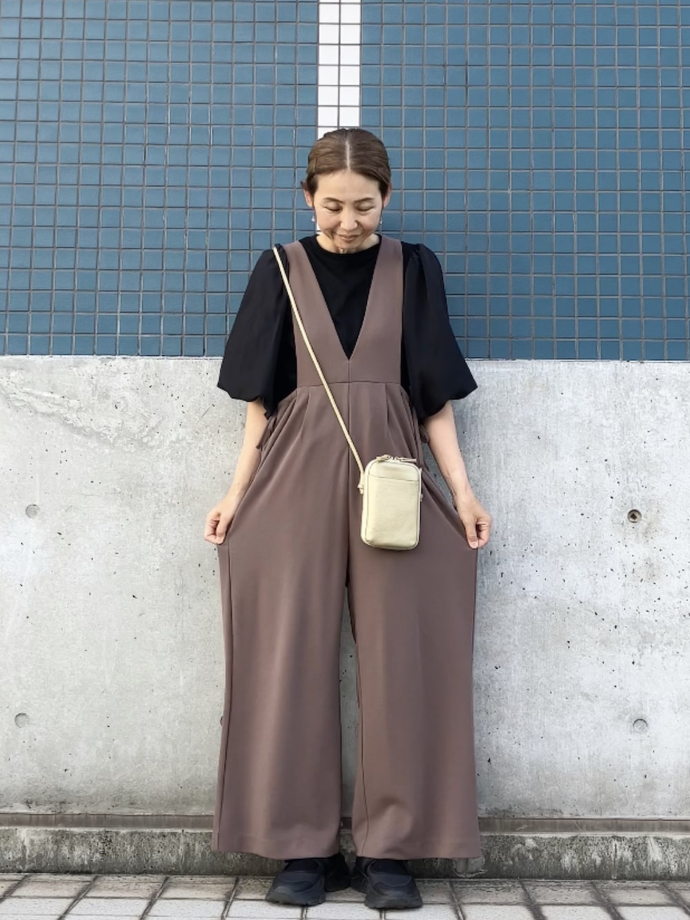 ブラウン系のサロペット/オーバーオール、ブラック系のTシャツ/カットソー、ゴールド系のバッグを着用したレディースの夏コーディネートの3枚目の写真