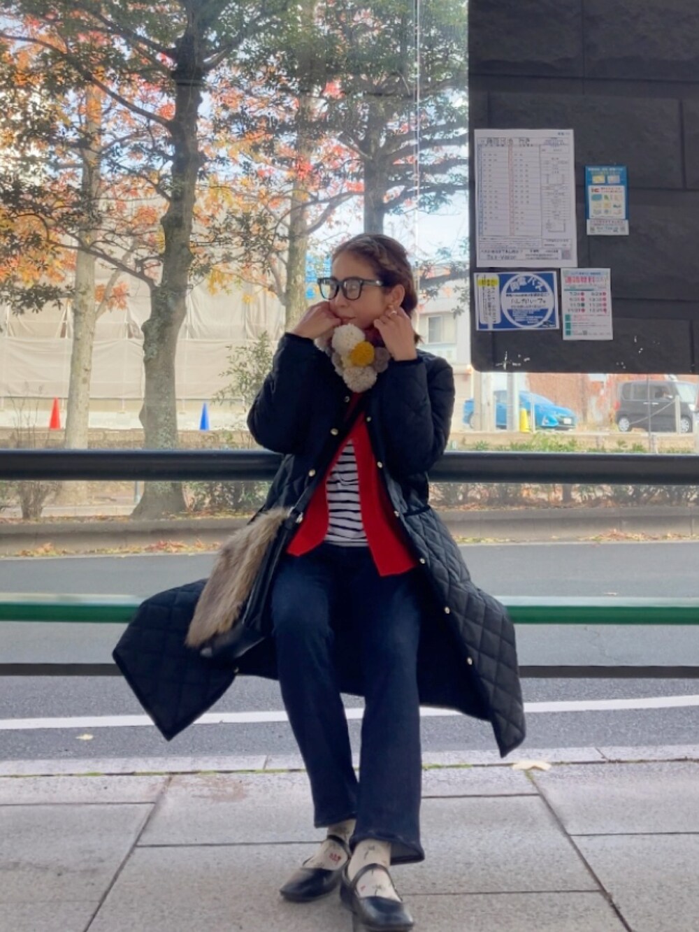 ブラック系のその他アウター、レッド系のカーディガン/ボレロ、ブルー系のデニムパンツを着用したレディースの冬コーディネートの3枚目の写真