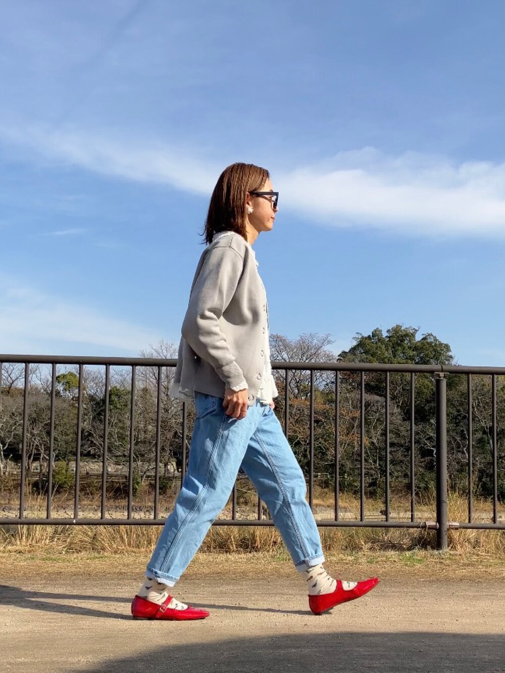 レッド系のパンプス、ホワイト系のシャツ/ブラウス、グレー系のカーディガン/ボレロを着用したレディースの冬コーディネートの3枚目の写真