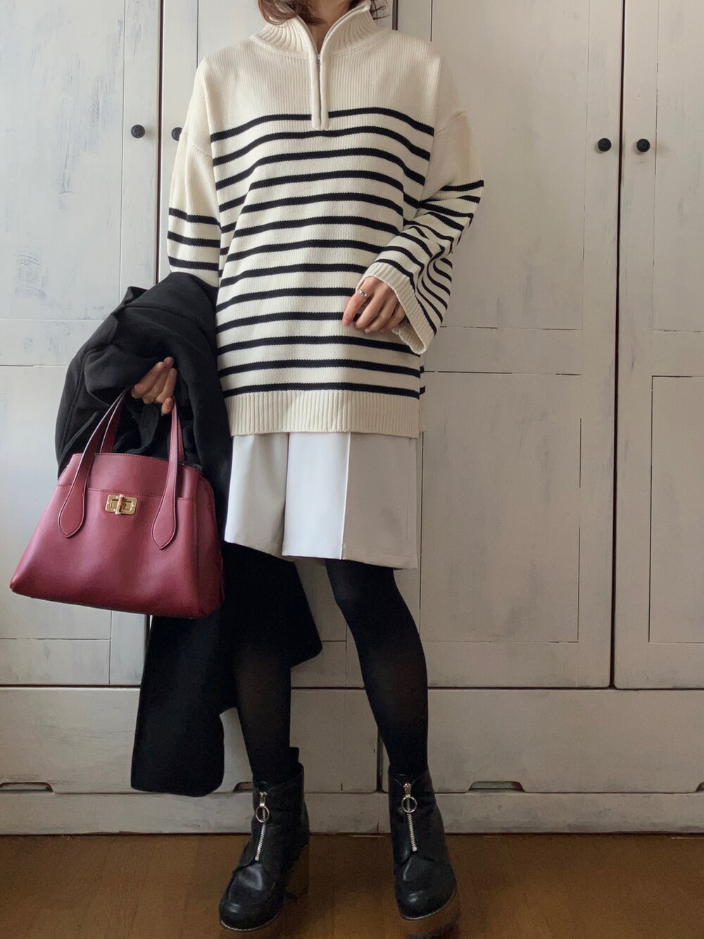 ブラック系のステンカラーコート、ホワイト系のニット/セーター、ベージュ系のその他パンツを着用したレディースの冬コーディネートの3枚目の写真