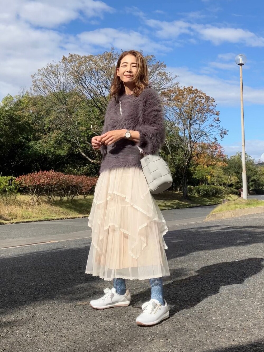 ベージュ系のスカート、グレー系のニット/セーター、グレー系のハンドバッグを着用したレディースの秋コーディネートの2枚目の写真