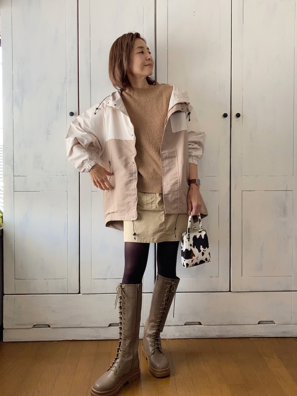 ベージュ系のマウンテンパーカー、ベージュ系のベスト、ベージュ系のスカートを着用したレディースの秋コーディネートの4枚目の写真
