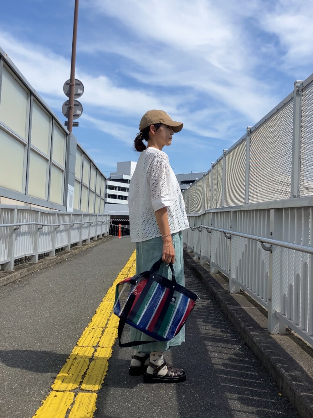 レッド系のバッグ、ベージュ系のキャップを着用したレディースの夏コーディネートの5枚目の写真