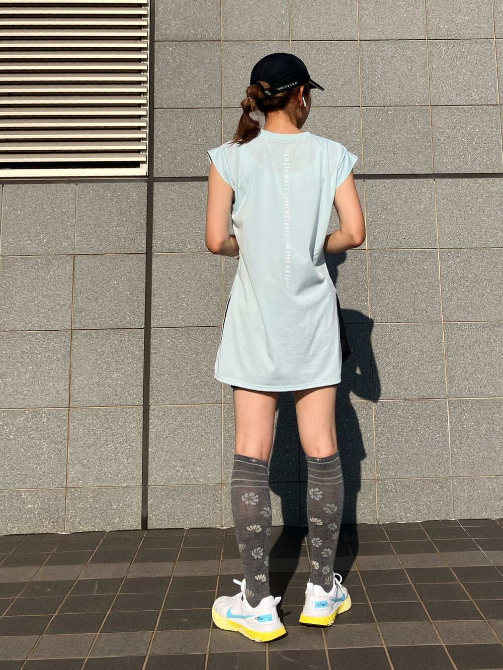 ブラック系のワンピース、ブルー系のTシャツ/カットソー、ホワイト系のスニーカーを着用したレディースの夏コーディネートの3枚目の写真