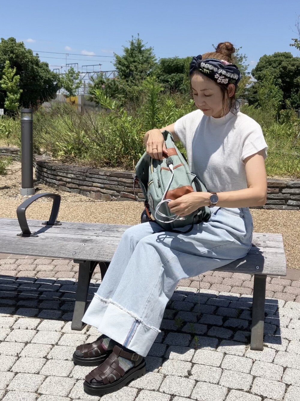 グリーン系のバックパック/リュック、ホワイト系のTシャツ/カットソー、ブルー系のデニムパンツを着用したレディースの夏コーディネートの2枚目の写真