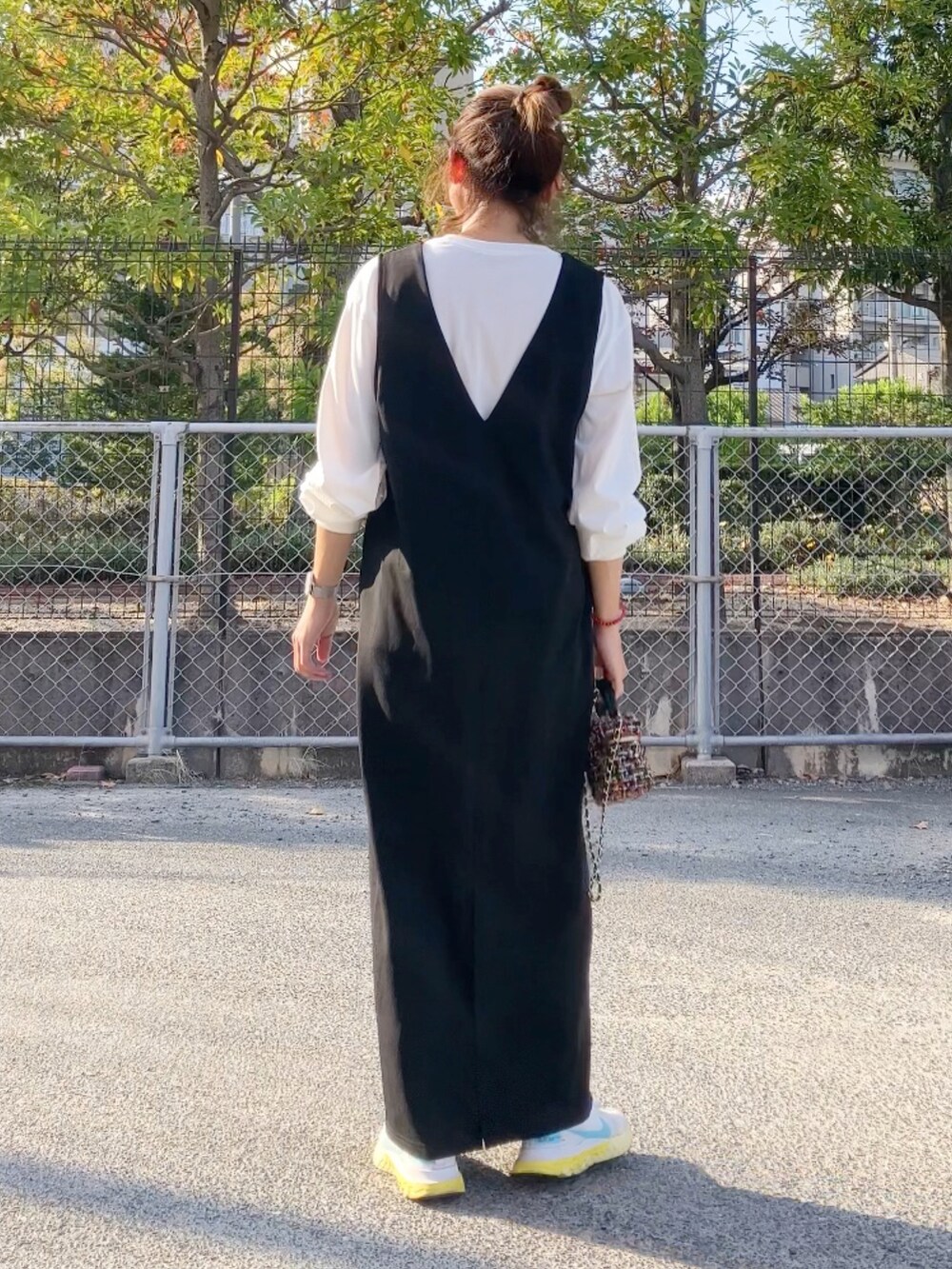 ブラック系のジャンパースカート、その他のハンドバッグ、ホワイト系のスニーカーを着用したレディースの秋コーディネートの2枚目の写真