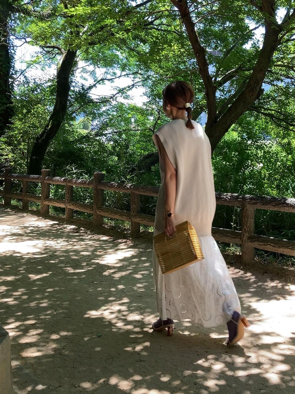 ベージュ系のかごバッグ、ベージュ系のベスト、ホワイト系のワンピース/ドレスを着用したレディースの夏コーディネートの3枚目の写真