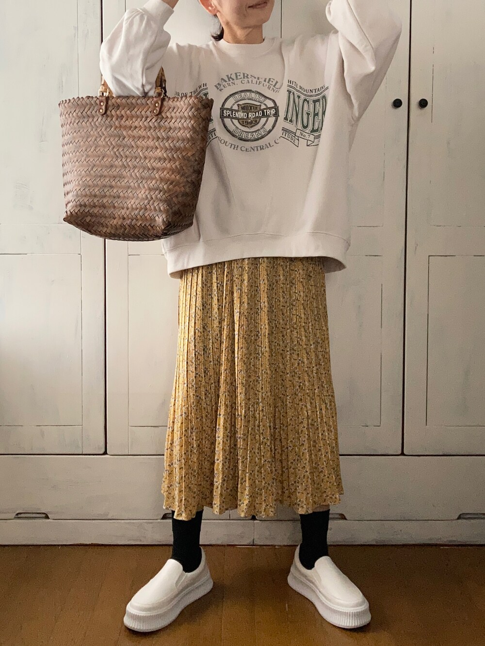 ホワイト系のスウェット、イエロー系のスカート、ホワイト系のスリッポンを着用したレディースの春コーディネートの2枚目の写真