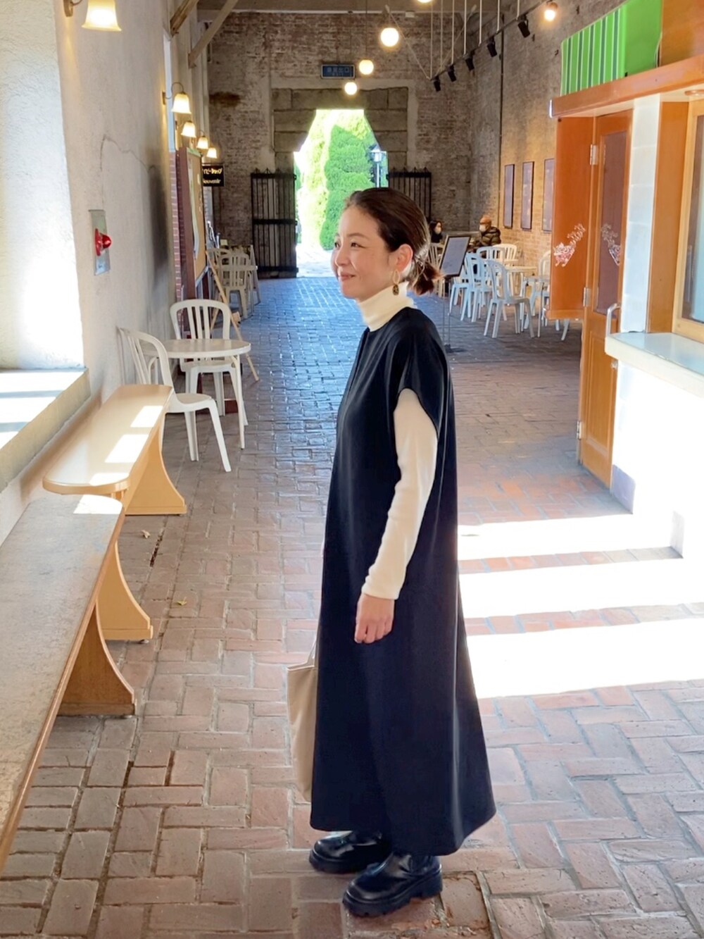 ブラック系のワンピース、ブラック系のブーツ、ベージュ系のトートバッグを着用したレディースの冬コーディネートの3枚目の写真