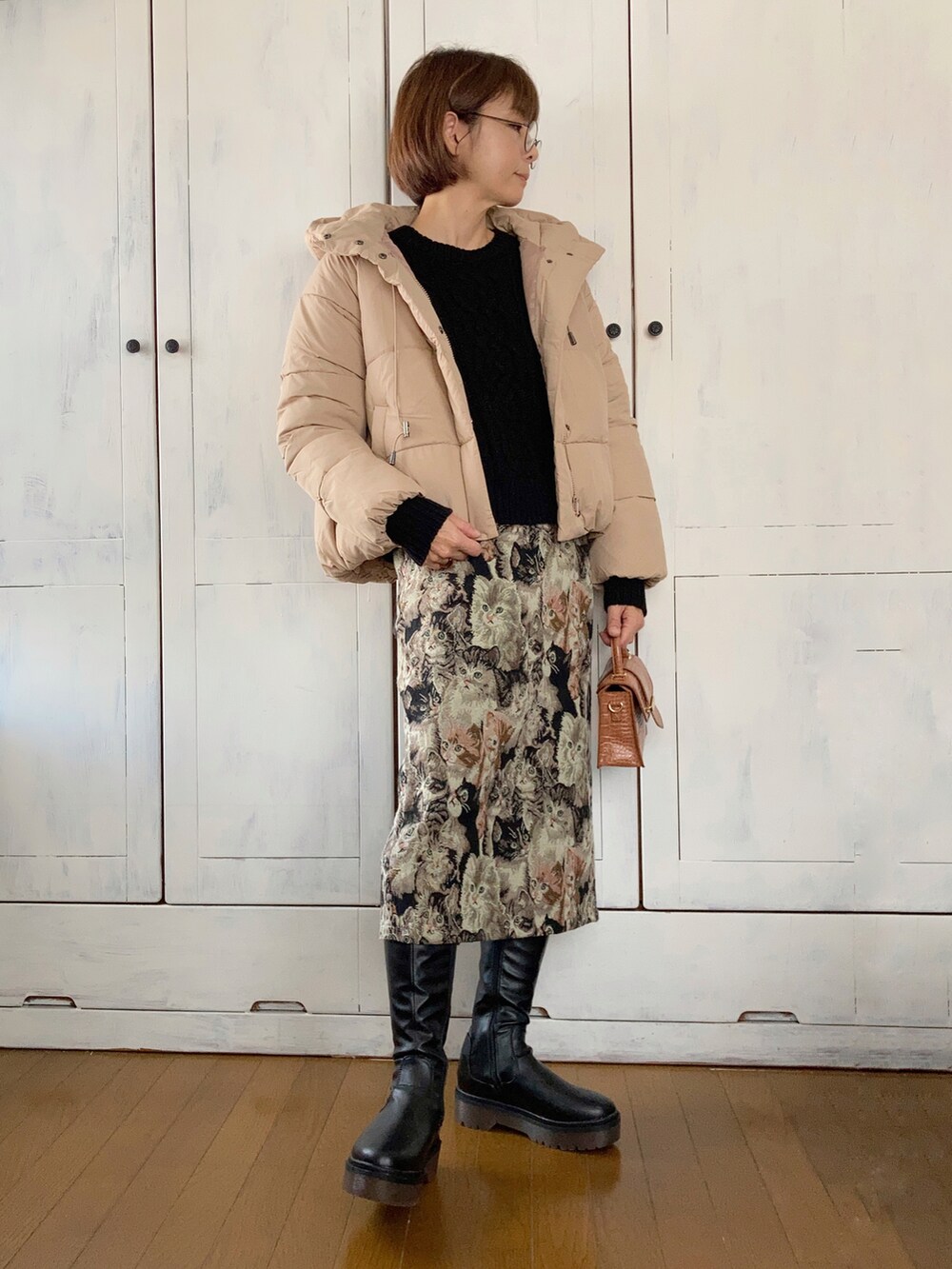 ベージュ系のダウンジャケット/コート、ブラック系のニット/セーター、ブラック系のスカートを着用したレディースの秋コーディネートの2枚目の写真