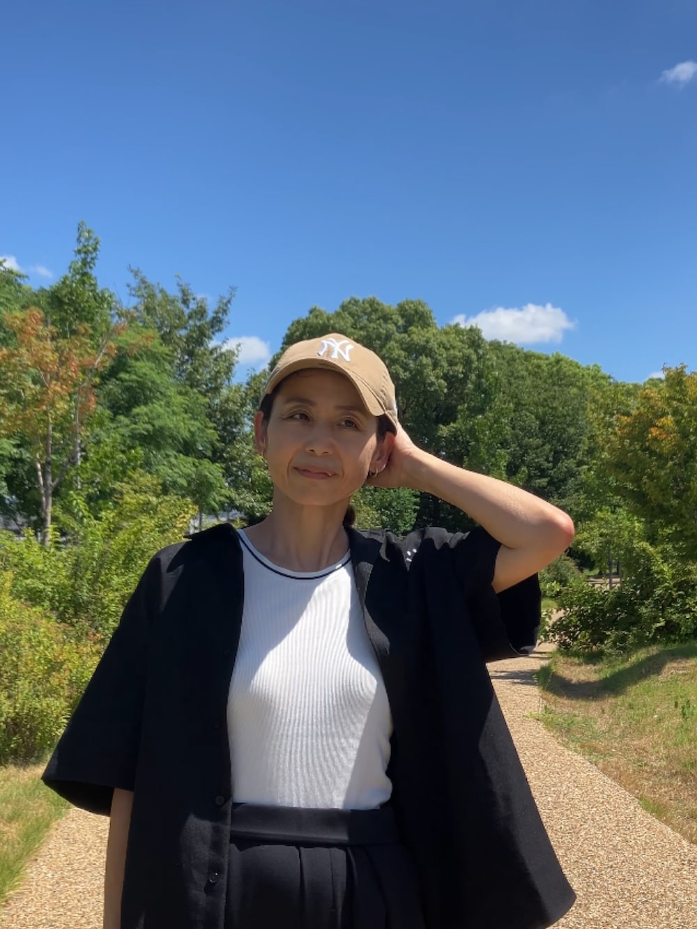 ブラック系のスラックス、イエロー系のサンダル、ベージュ系のキャップを着用したレディースの夏コーディネートの3枚目の写真