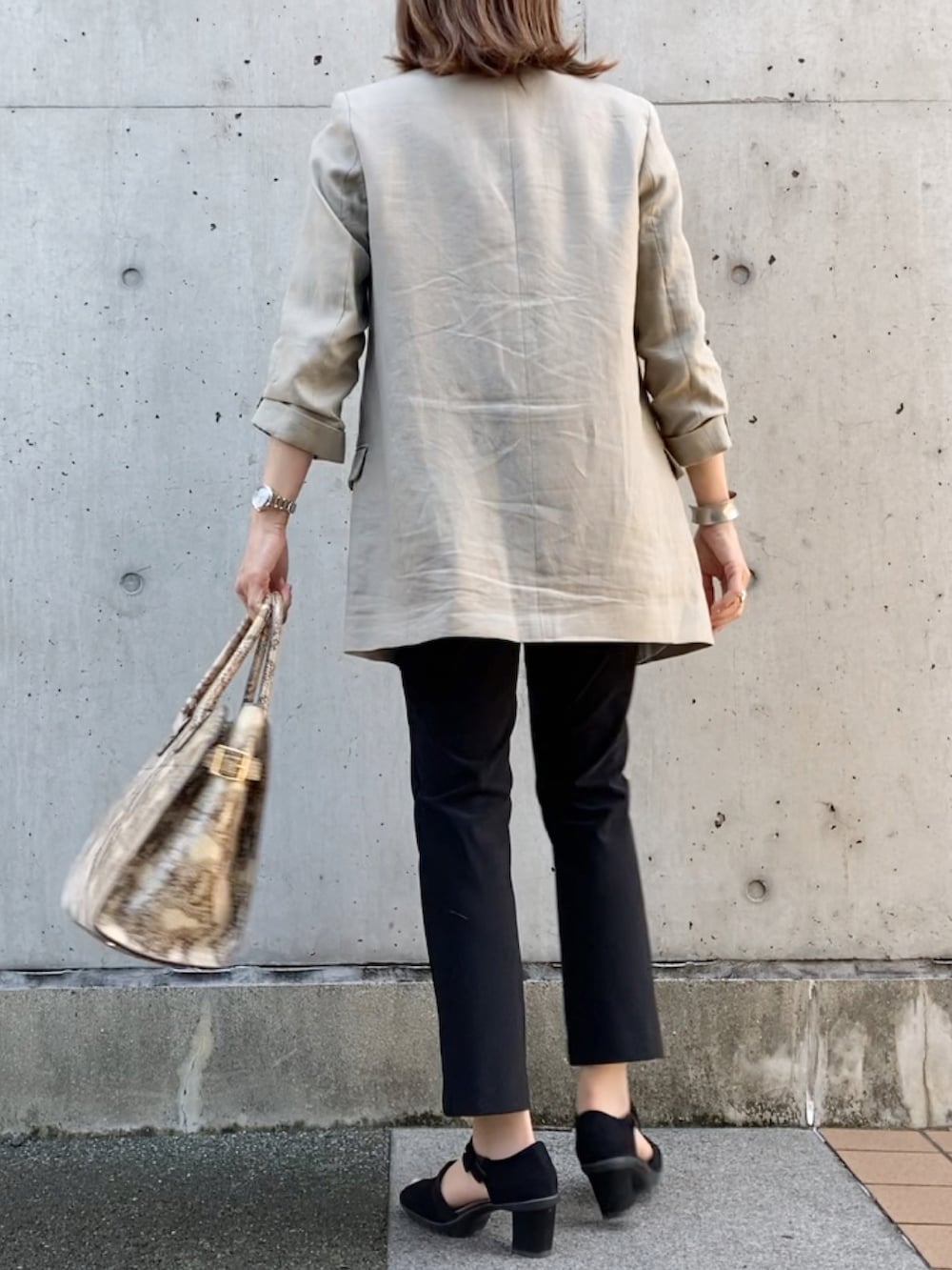 ブラック系のパンツ、ベージュ系のジャケット/アウター、ホワイト系のTシャツ/カットソーを着用したレディースの夏コーディネートの3枚目の写真