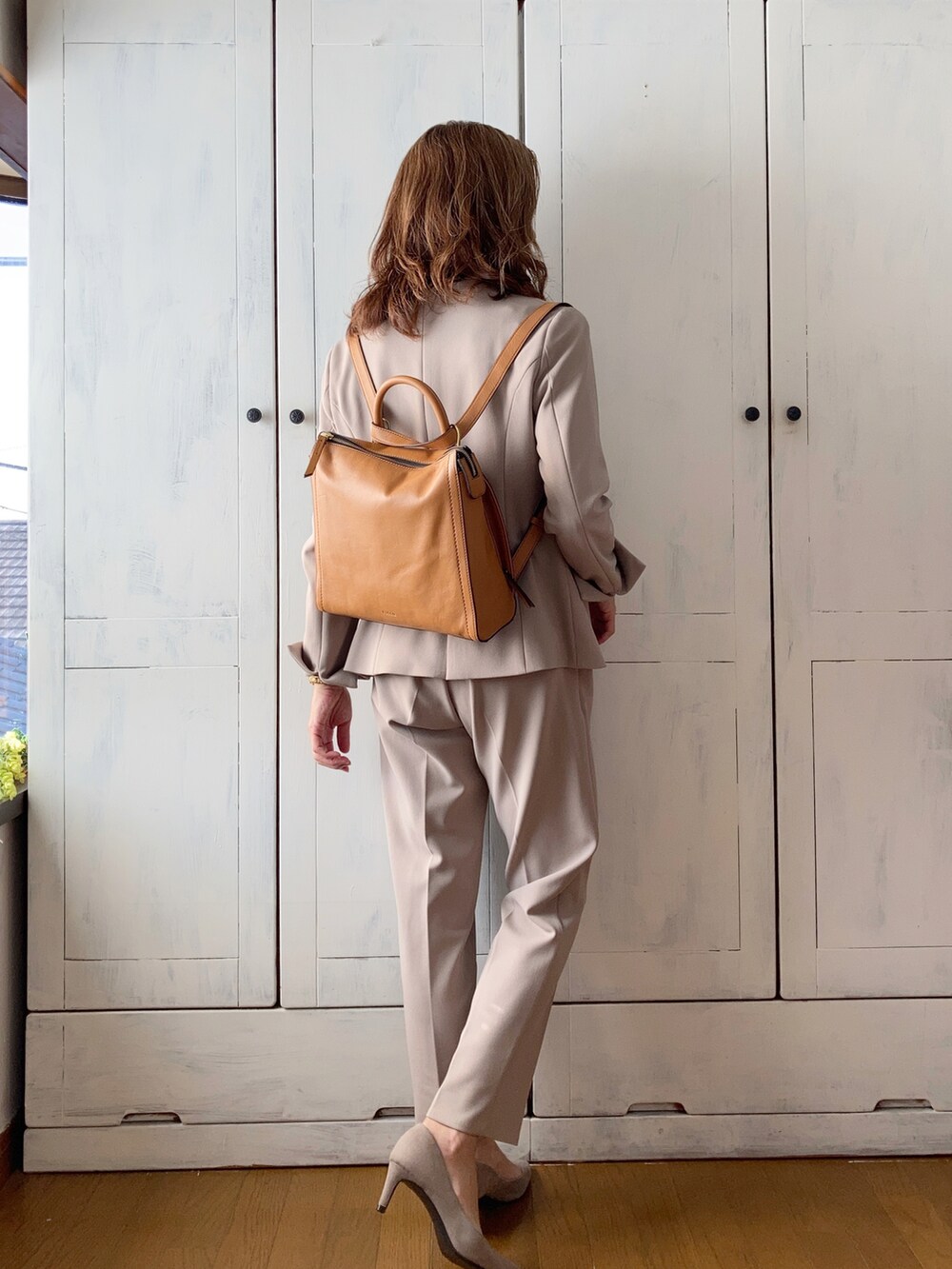 ベージュ系のスーツセット、イエロー系のバックパック/リュック、ブラック系のニット/セーターを着用したレディースの秋コーディネートの3枚目の写真