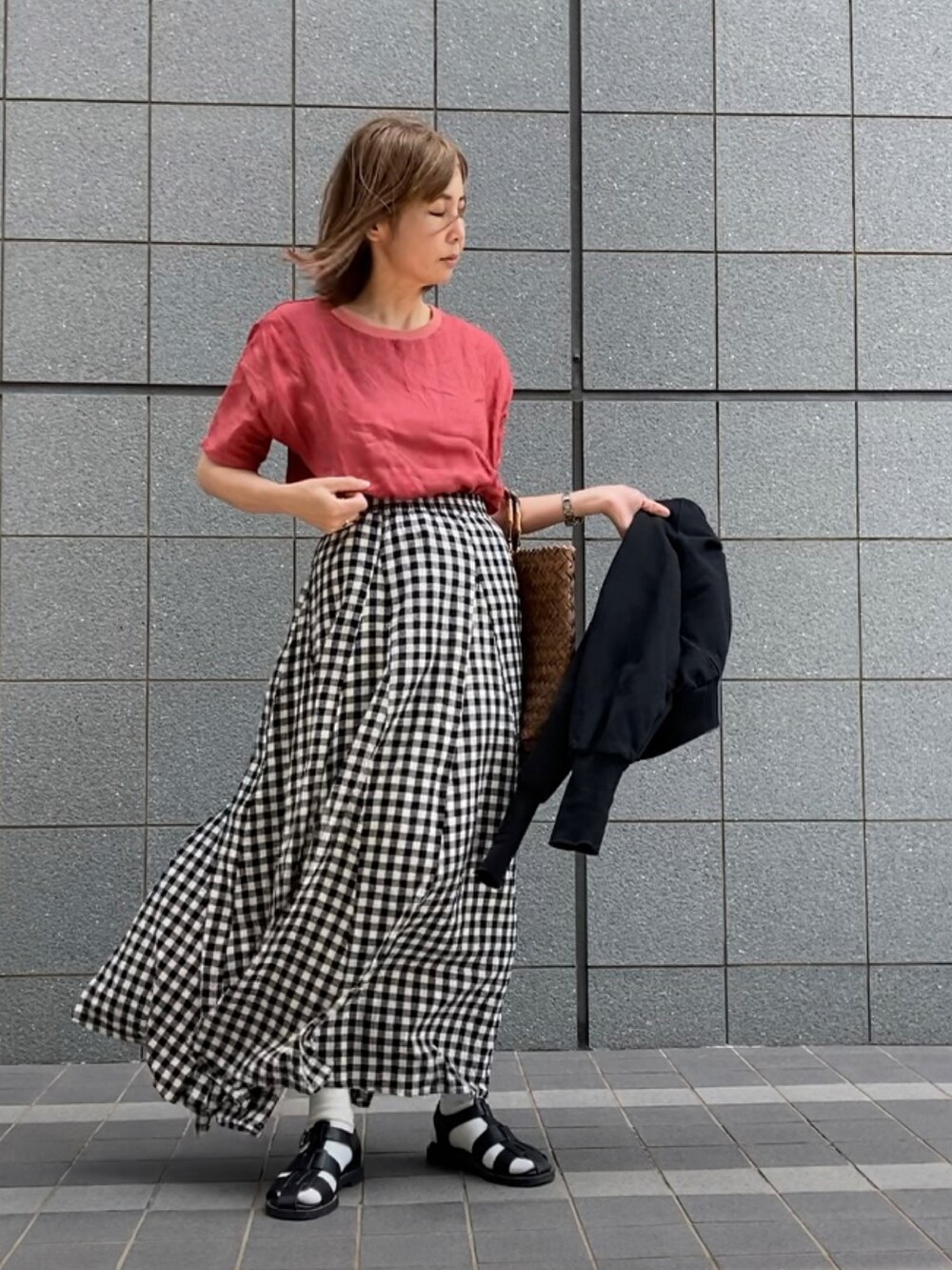 レッド系のトップス、ブラック系のスカート、ブラック系のスウェットを着用したレディースの春コーディネートの2枚目の写真