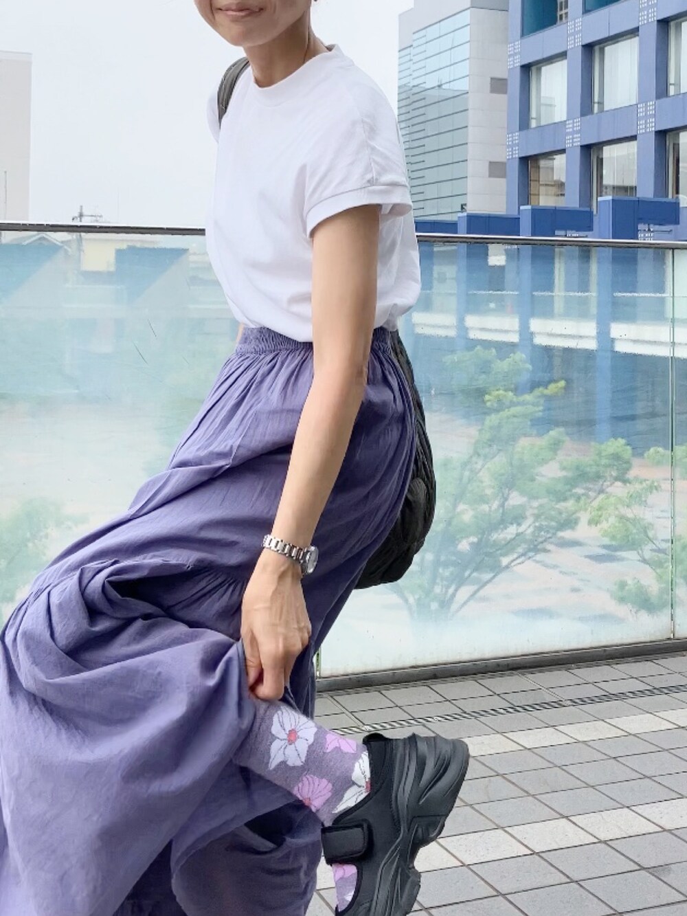 グレー系のスカート、ホワイト系のTシャツ/カットソー、グレー系のショルダーバッグを着用したレディースの夏コーディネートの2枚目の写真