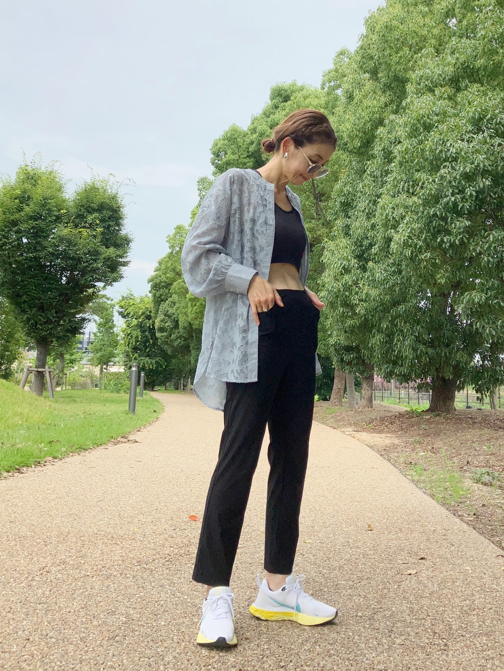 ブラック系のパンツ、ブルー系のシャツ/ブラウス、ホワイト系のスニーカーを着用したレディースの夏コーディネートの2枚目の写真