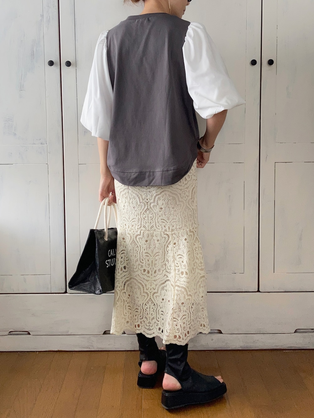 ブラック系のその他トップス、ホワイト系のスカート、ブラック系のブーツを着用したレディースの春コーディネートの2枚目の写真