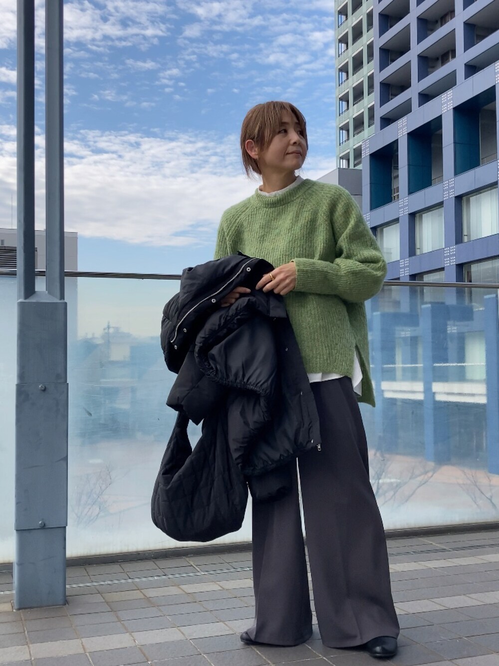 ブラック系のダウンジャケット/コート、グリーン系のニット/セーター、グレー系のその他パンツを着用したレディースの冬コーディネートの2枚目の写真