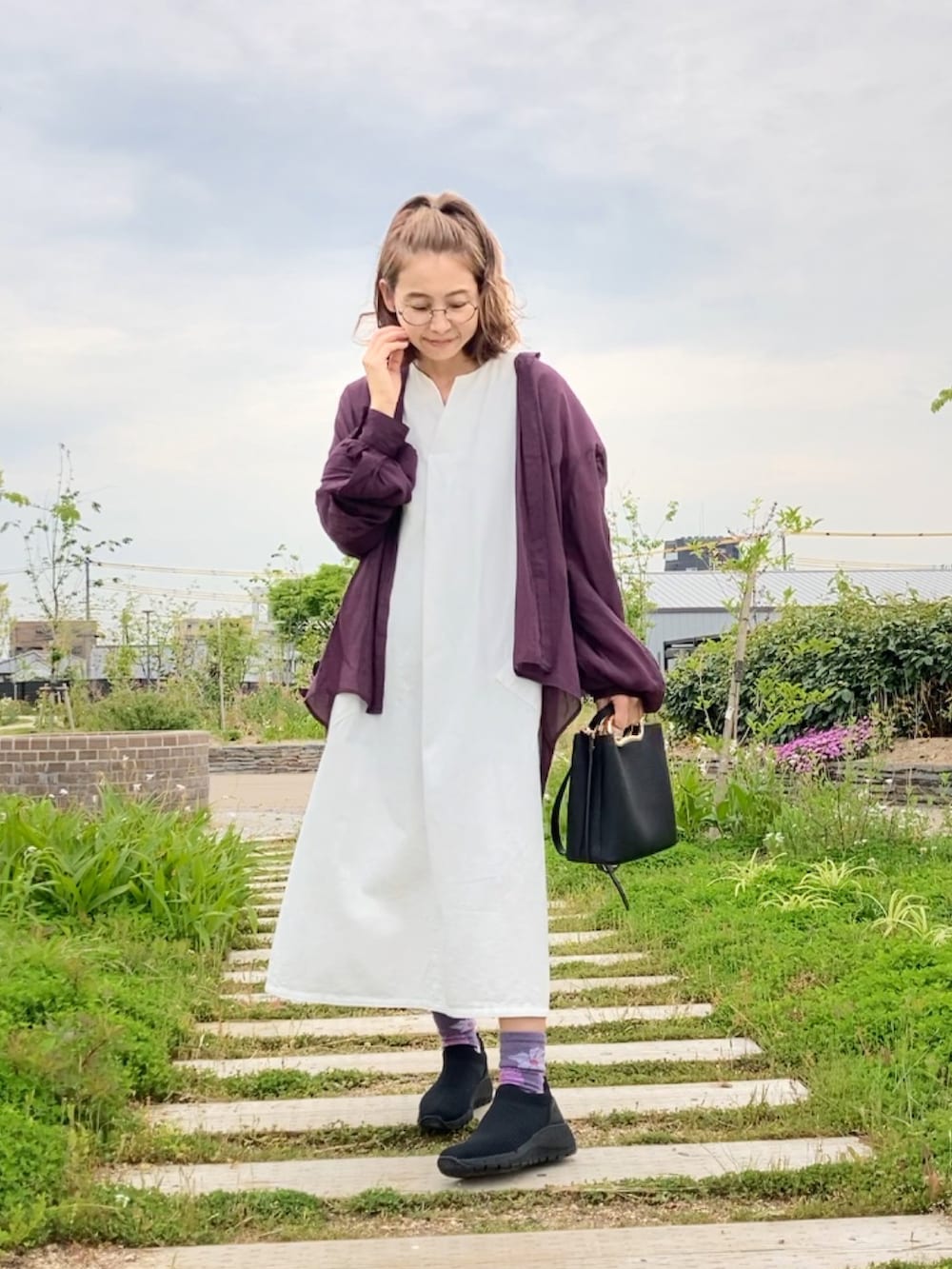 ブラック系のシューズ、ブラック系のハンドバッグ、ホワイト系のワンピースを着用したレディースの春コーディネートの2枚目の写真