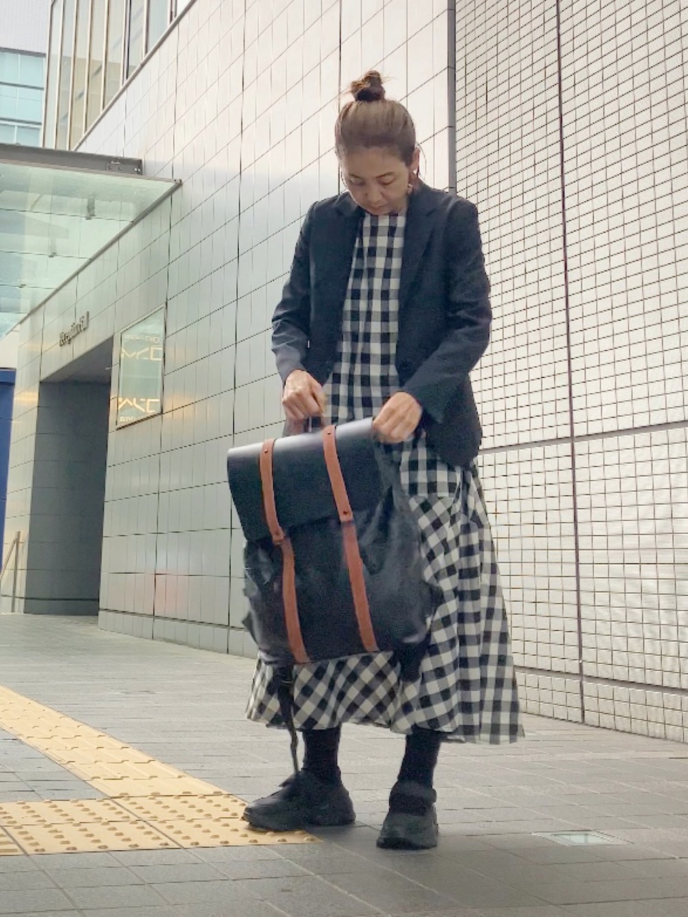 ブラック系のワンピース、ブラック系のスーツセット、ブラウン系のバックパック/リュックを着用したレディースの春コーディネートの4枚目の写真