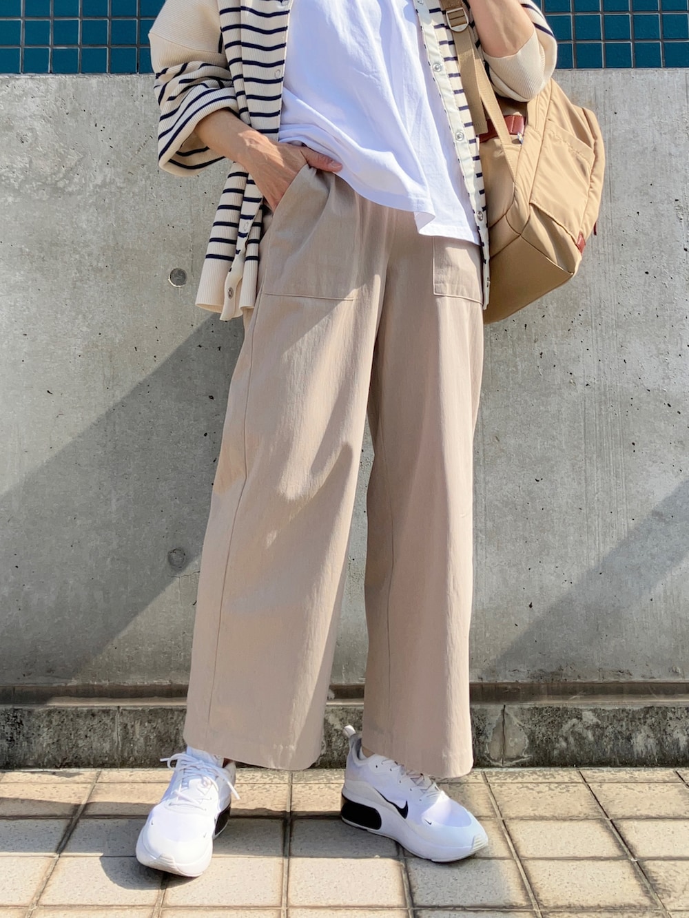 ベージュ系のパンツ、ホワイト系のTシャツ/カットソー、ブルー系のカーディガン/ボレロを着用したレディースの春コーディネートの2枚目の写真