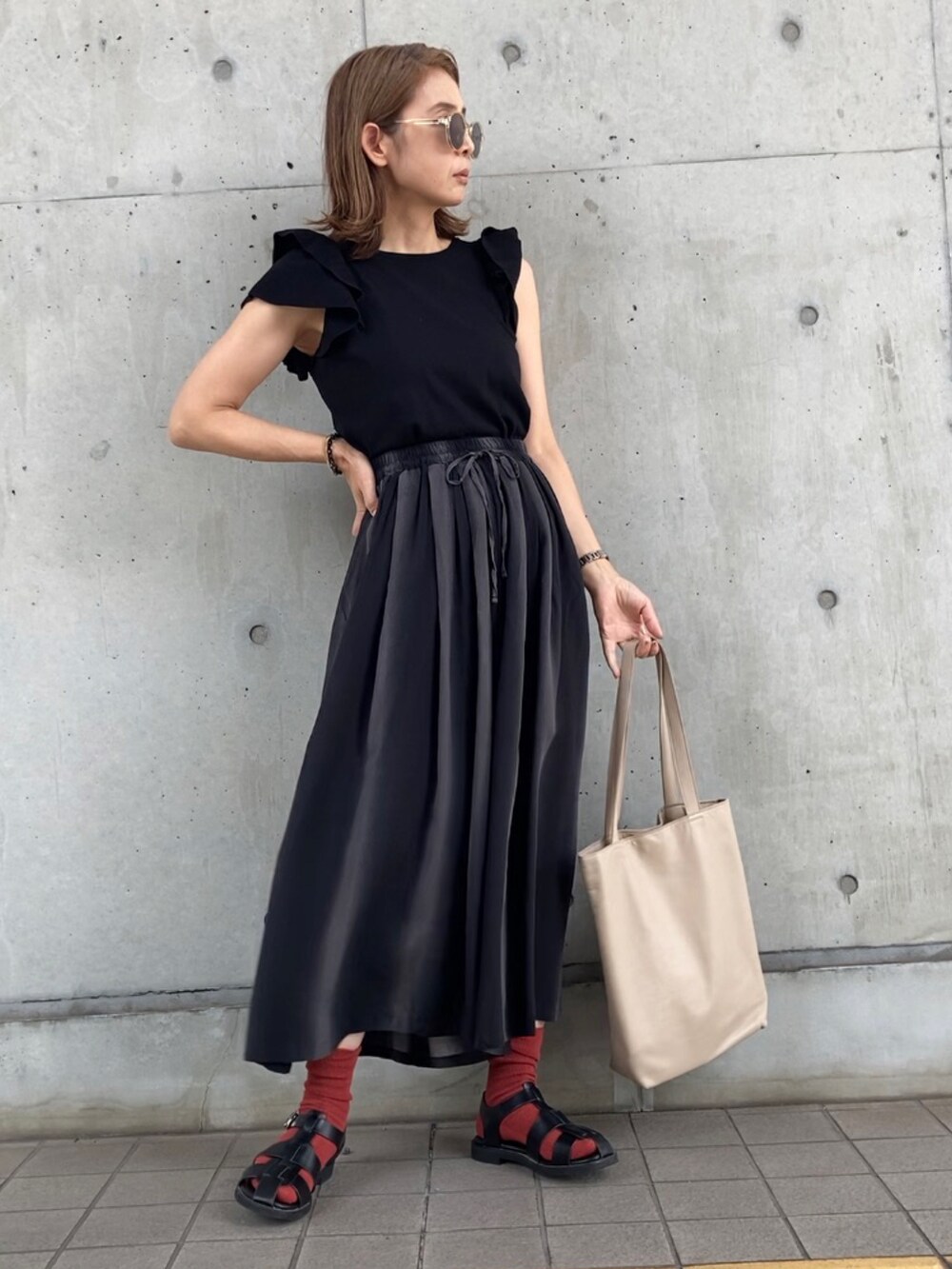 グレー系のパンツ、ブラック系のニット/セーター、ブラック系のサンダルを着用したレディースの春コーディネートの2枚目の写真