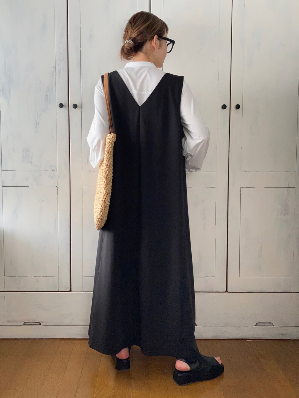 ブラック系のジャンパースカート、ホワイト系のワンピース/ドレス、ベージュ系のバッグを着用したレディースの春コーディネートの3枚目の写真