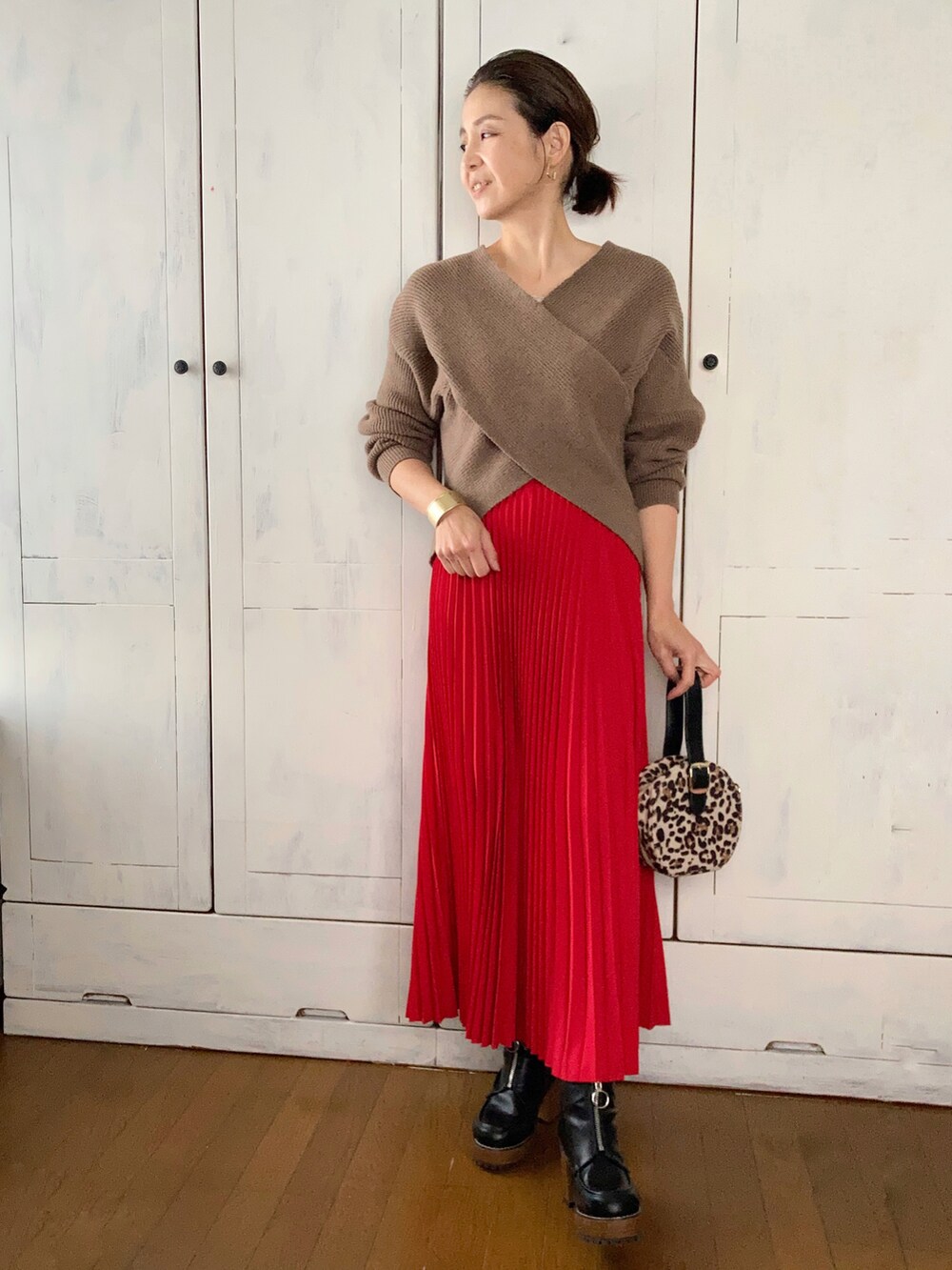 ブラック系のダウンジャケット/コート、ブラウン系のニット/セーター、レッド系のスカートを着用したレディースの冬コーディネートの2枚目の写真