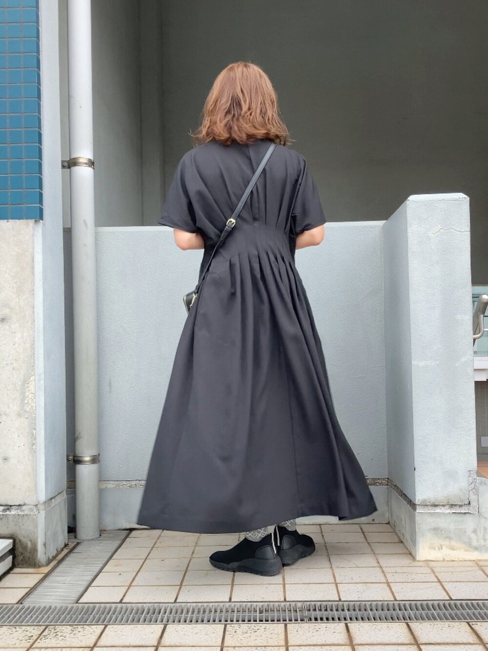 ブラック系のワンピース、ホワイト系のチノパンツ、ブラック系のシューズを着用したレディースの夏コーディネートの2枚目の写真