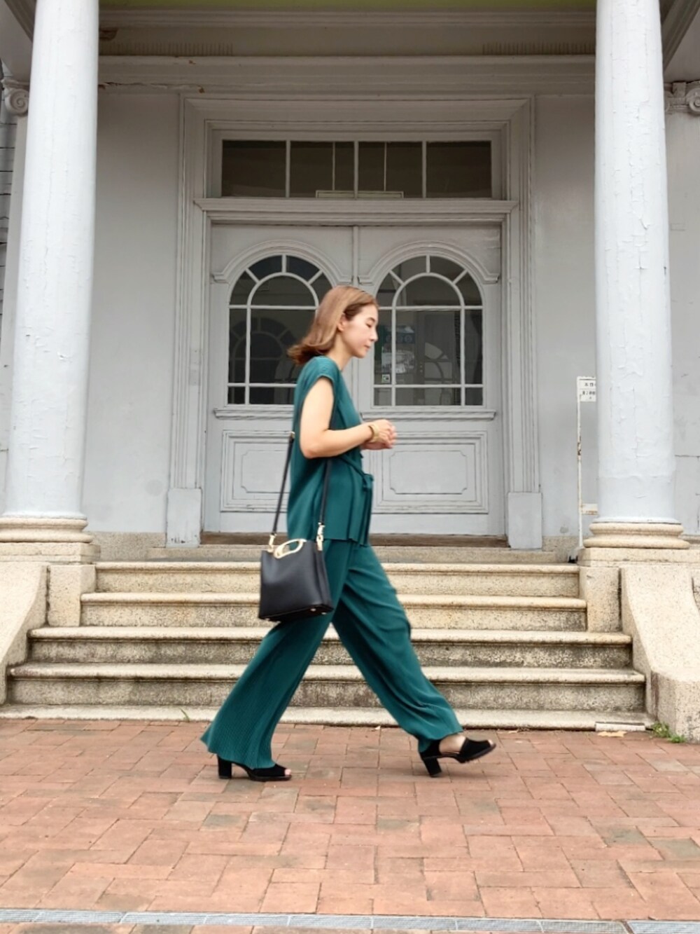 グリーン系のパンツ、ブラック系のハンドバッグ、ブラック系のサンダルを着用したレディースの夏コーディネートの5枚目の写真