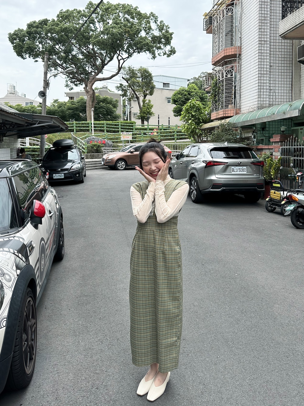 ベージュ系のトップス、グリーン系のジャンパースカート、ホワイト系のドレスシューズを着用したレディースの春コーディネートの2枚目の写真