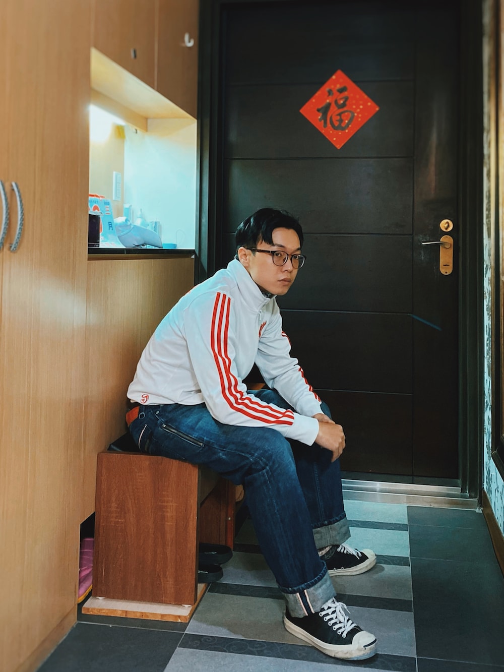 ブルー系のデニムパンツ、ブラック系のスニーカー、ホワイト系のスタジャンを着用したメンズの春コーディネートの3枚目の写真