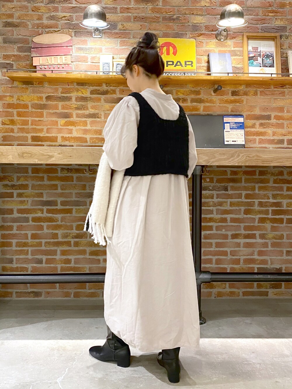ブラック系のベスト、ホワイト系のワンピース、ブラック系のブーツを着用したレディースの冬コーディネートの3枚目の写真