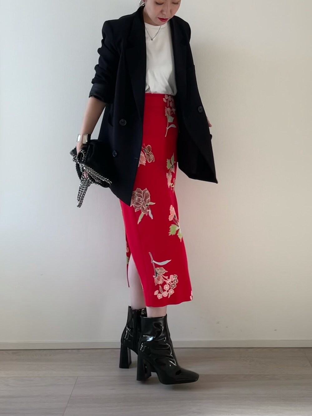 レッド系のスカート、ブラック系のブーツ、ブラック系のジャケット/アウターを着用したレディースの秋コーディネートの3枚目の写真