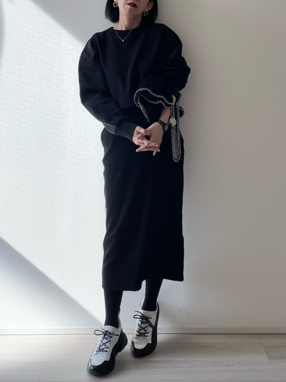 ブラック系のスニーカー、ブラック系のスウェット、ブラック系のスカートを着用したレディースの秋コーディネートの2枚目の写真