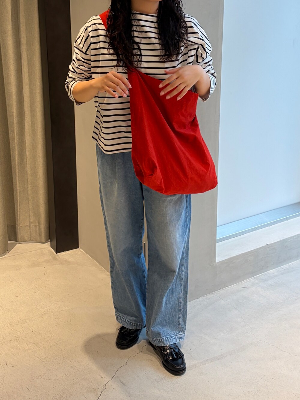 レッド系のショルダーバッグ、ブルー系のデニムパンツ、ブラック系のTシャツ/カットソーを着用したレディースの春コーディネートの3枚目の写真