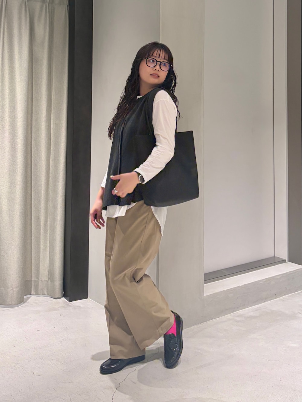 グレー系のベスト、ホワイト系のTシャツ/カットソー、ブラック系のトートバッグを着用したレディースの秋コーディネートの3枚目の写真