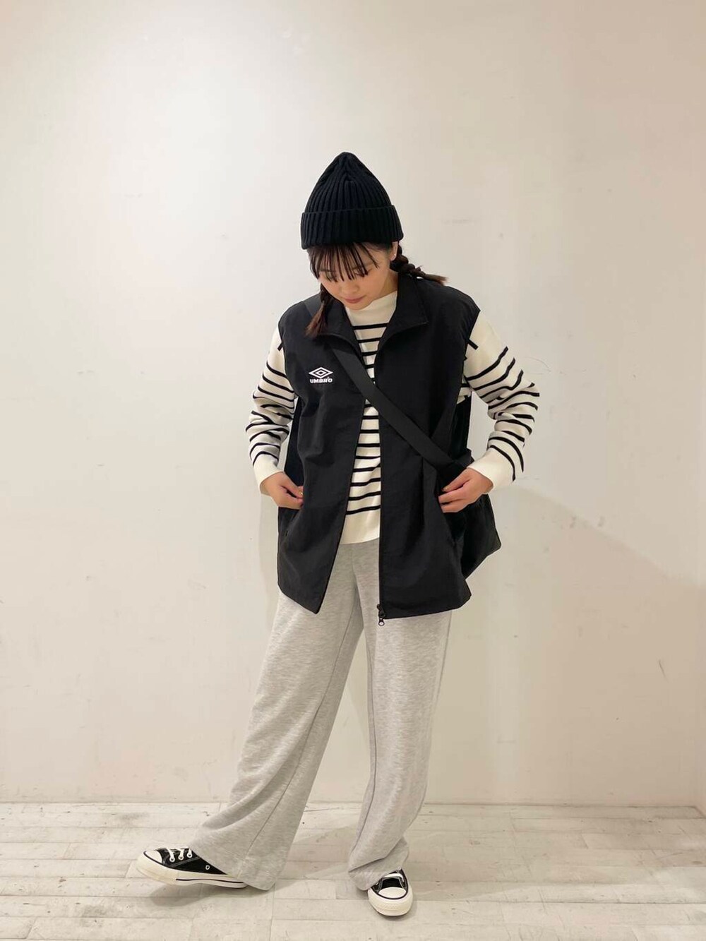 ブラック系のスニーカー、ブラック系のショルダーバッグ、ブラック系のベストを着用したレディースの秋コーディネートの3枚目の写真