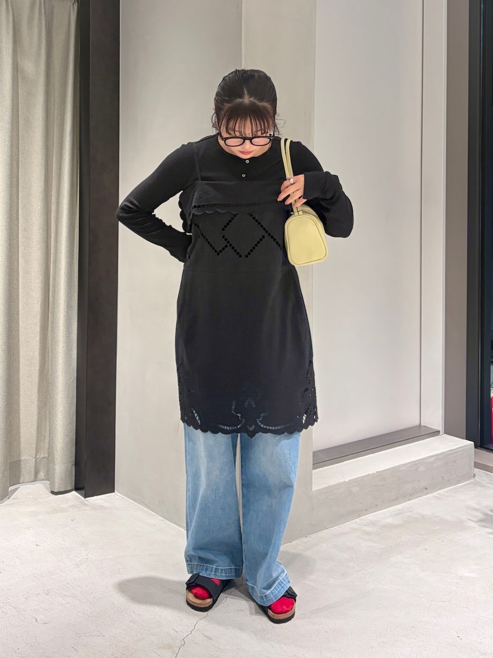 ブルー系のデニムパンツ、ブラック系のカーディガン/ボレロ、イエロー系のハンドバッグを着用したレディースの夏コーディネートの5枚目の写真